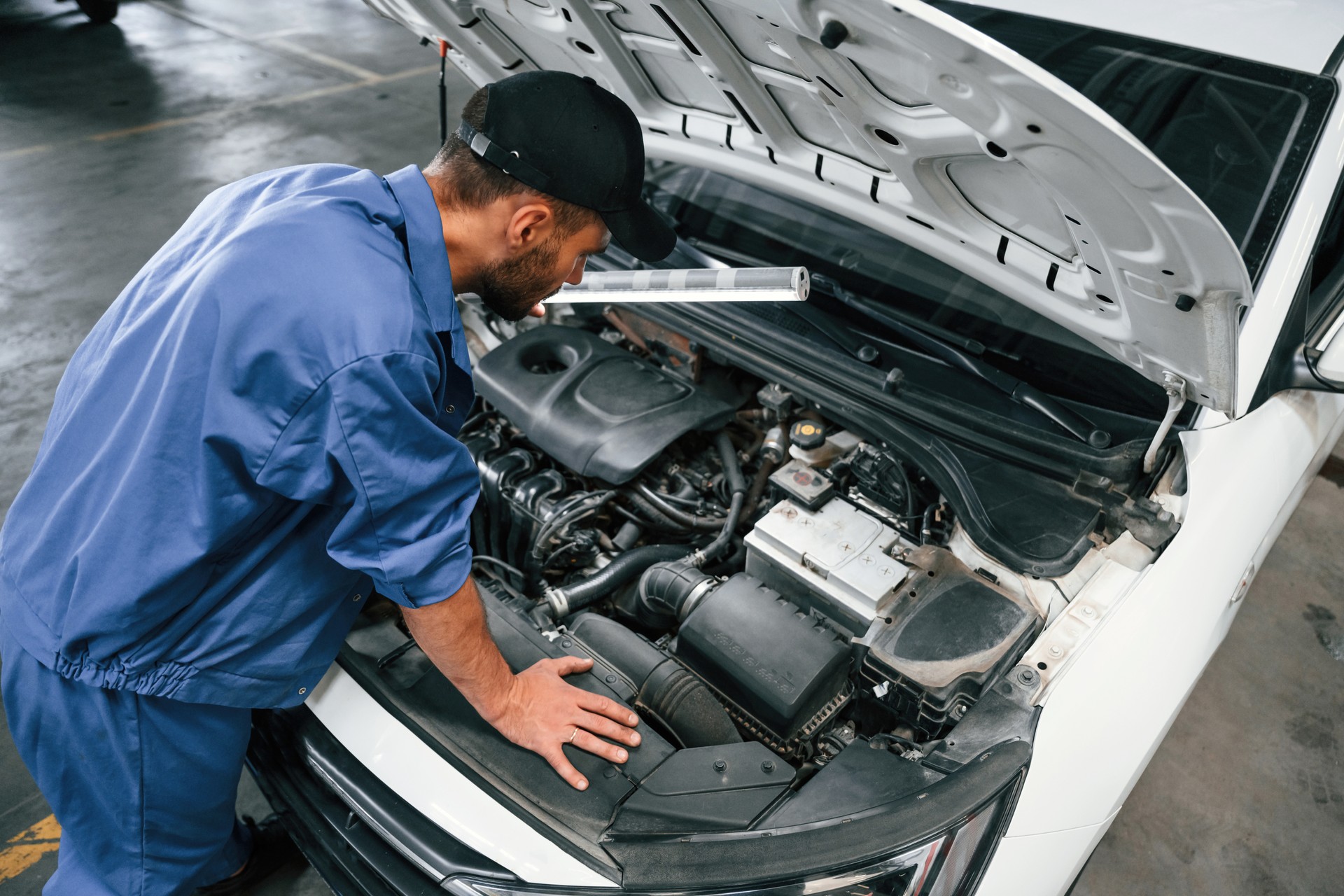 Vista superior. La campana está abierta. Mecánico de automóviles trabajando en garaje. Servicio de reparación